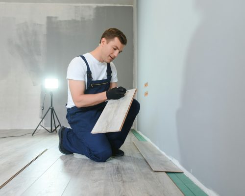 Repairman laying laminate flooring at home